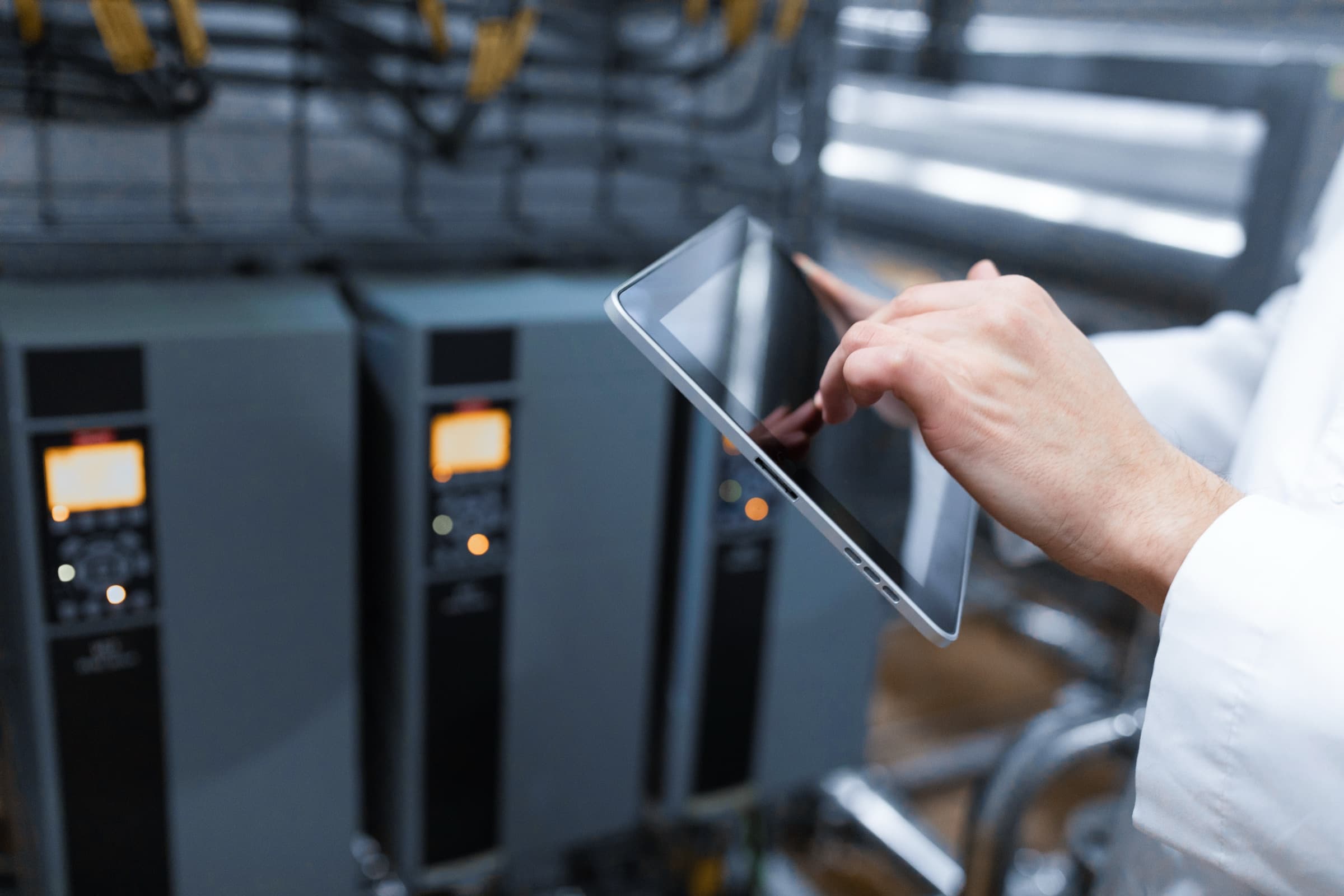 Une main annote une tablette devant des baies de stockage.
